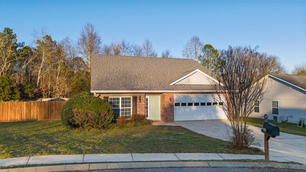 front of property with a garage, central air condition unit, and a front yard