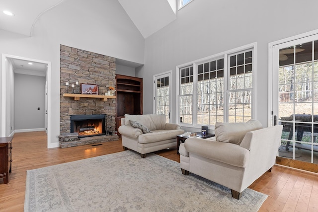 living room featuring hardwood / wood-style flooring, a stone fireplace, and high vaulted ceiling