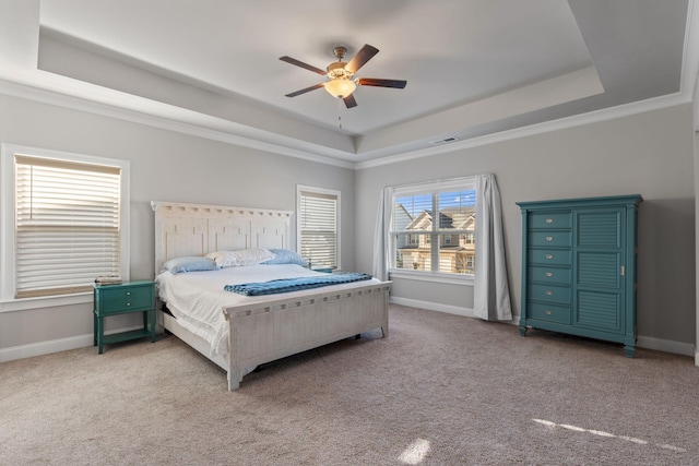 carpeted bedroom with a tray ceiling, ceiling fan, and crown molding