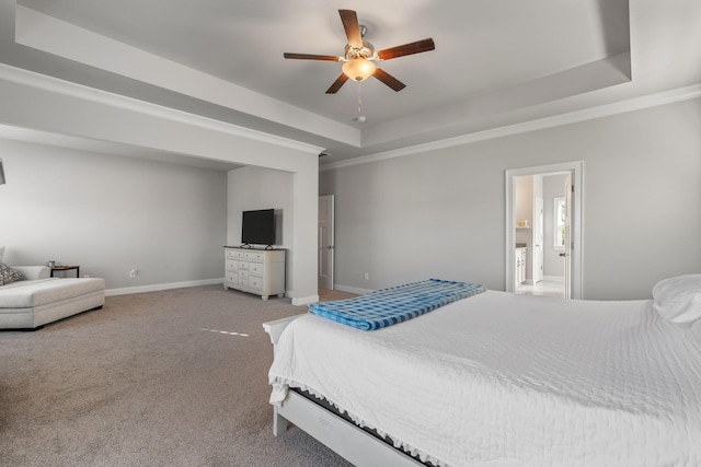 carpeted bedroom with ceiling fan, a raised ceiling, and connected bathroom