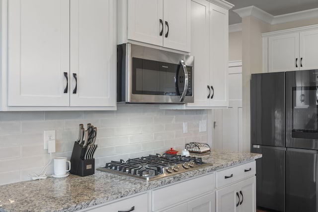 kitchen with backsplash, light stone counters, white cabinets, and stainless steel appliances