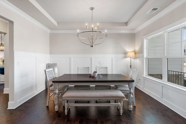 dining area featuring dark hardwood / wood-style flooring, a tray ceiling, crown molding, and a notable chandelier