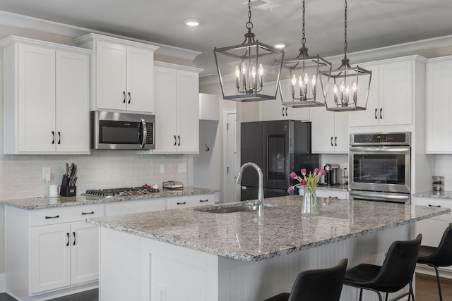 kitchen featuring a kitchen island with sink, pendant lighting, white cabinets, and stainless steel appliances