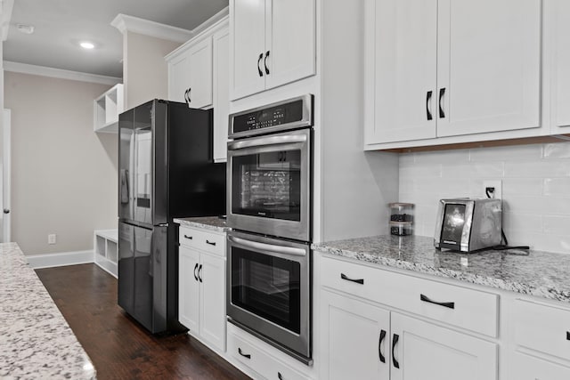 kitchen with white cabinetry, black fridge, dark wood-type flooring, and light stone counters