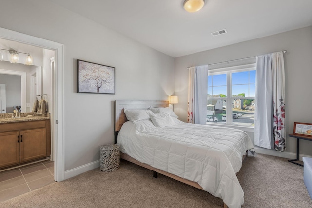 bedroom featuring connected bathroom, sink, and light colored carpet