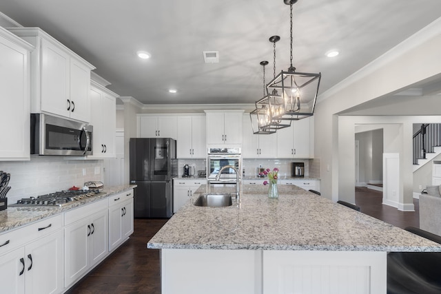 kitchen featuring appliances with stainless steel finishes, white cabinetry, a kitchen island with sink, and sink