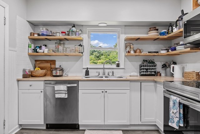 kitchen with backsplash, stainless steel appliances, sink, hardwood / wood-style flooring, and white cabinetry