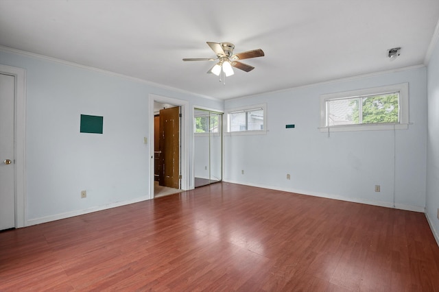 unfurnished bedroom featuring ornamental molding, wood finished floors, baseboards, and multiple windows