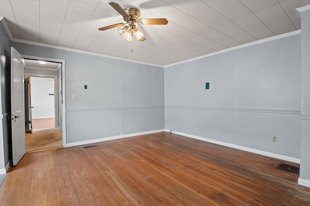 spare room with ornamental molding, visible vents, ceiling fan, wood-type flooring, and baseboards