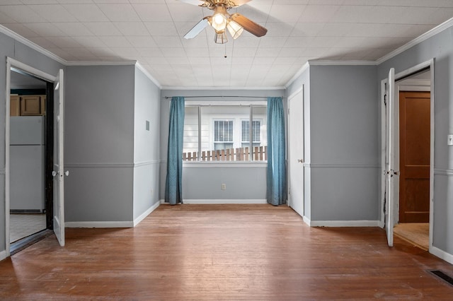 interior space featuring a ceiling fan, ornamental molding, baseboards, and wood finished floors