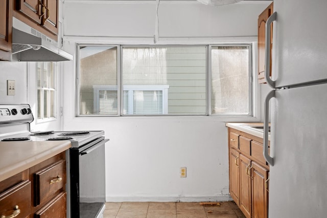 kitchen featuring freestanding refrigerator, under cabinet range hood, light countertops, light tile patterned floors, and electric range