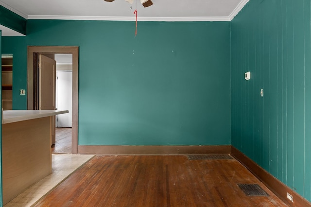 spare room with crown molding, visible vents, a ceiling fan, and hardwood / wood-style floors