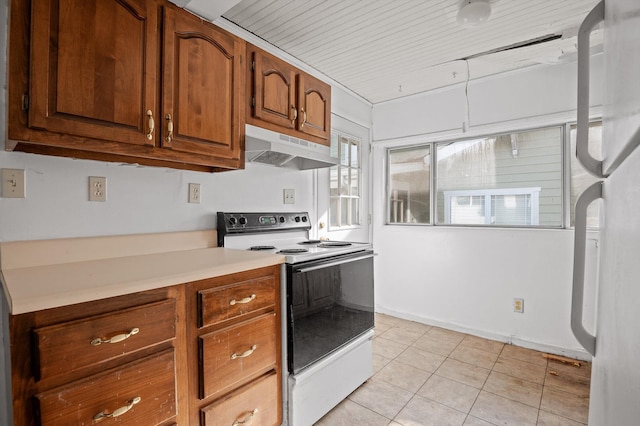 kitchen featuring under cabinet range hood, light tile patterned floors, white appliances, brown cabinets, and light countertops