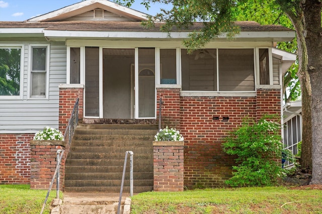 view of front of home featuring brick siding and a sunroom