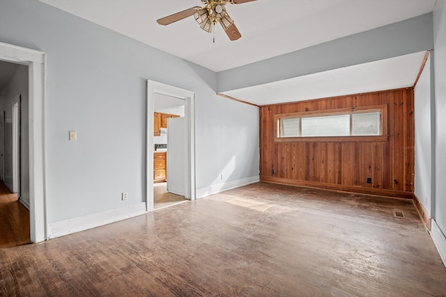 interior space featuring baseboards, ensuite bathroom, wooden walls, and wood finished floors