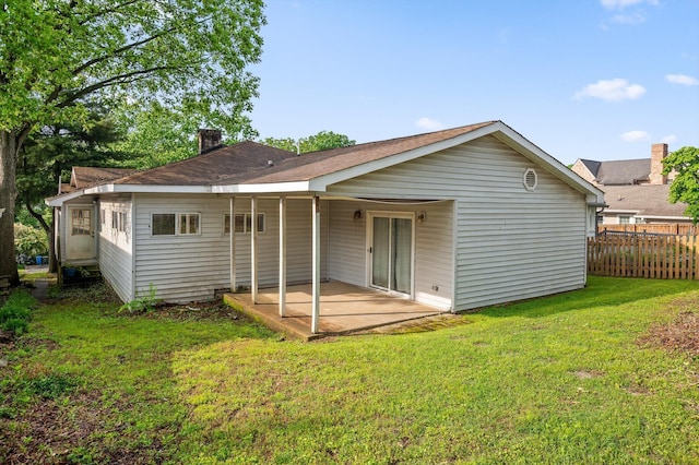 back of house featuring a patio area, a chimney, fence, and a lawn