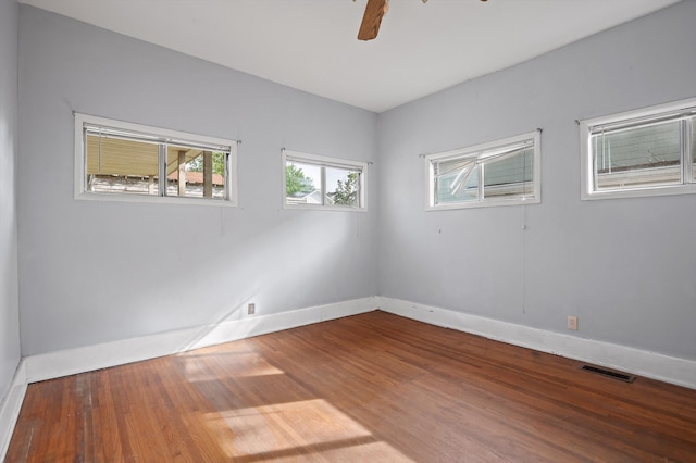 empty room featuring baseboards, a ceiling fan, visible vents, and wood finished floors