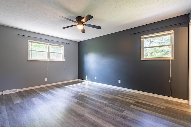 spare room featuring wood finished floors, a textured ceiling, visible vents, a ceiling fan, and baseboards