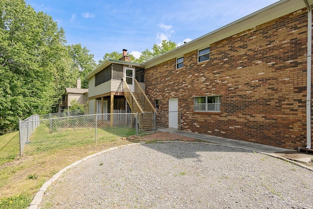 rear view of property with stairway, fence, brick siding, and a lawn