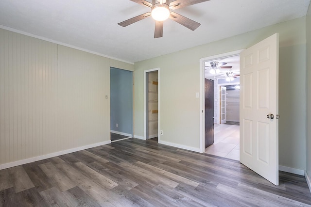 spare room featuring crown molding, baseboards, a ceiling fan, and wood finished floors