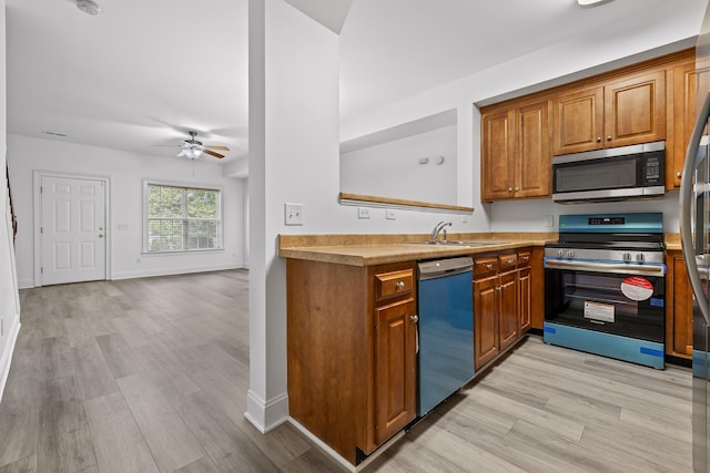 7510 Noah Reid Rd, Chattanooga, TN 37416 - kitchen with stainless steel appliances, a sink, brown cabinets, light wood-type flooring, and ceiling fan