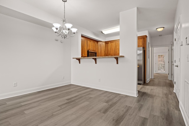 7510 Noah Reid Rd, Chattanooga, TN 37416 - kitchen with appliances with stainless steel finishes, a kitchen bar, brown cabinets, a chandelier, and light wood-style floors
