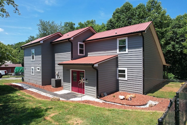 view of front of house with central AC and a front lawn