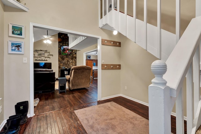 interior space with a fireplace, a high ceiling, hardwood / wood-style flooring, and ceiling fan