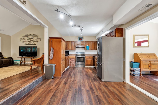 kitchen featuring appliances with stainless steel finishes, dark hardwood / wood-style flooring, rail lighting, a textured ceiling, and vaulted ceiling