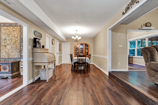 dining space featuring a chandelier, a textured ceiling, and dark wood-type flooring