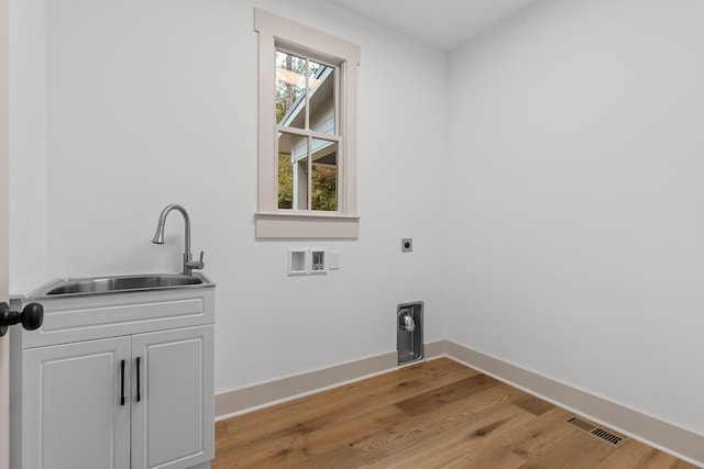 clothes washing area featuring cabinets, hookup for a washing machine, electric dryer hookup, sink, and light hardwood / wood-style flooring