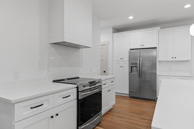 kitchen with white cabinetry, stainless steel appliances, custom range hood, and light hardwood / wood-style floors