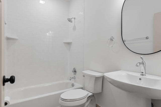 full bathroom featuring tiled shower / bath combo, toilet, and sink