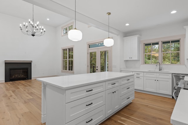 kitchen featuring white cabinets, light hardwood / wood-style flooring, a wealth of natural light, and hanging light fixtures