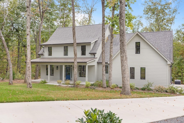 view of front of house with cooling unit, covered porch, and a front lawn