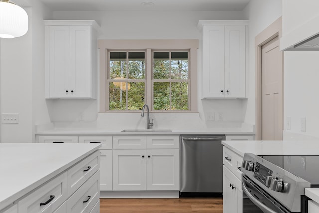 kitchen with white cabinets, stainless steel appliances, light hardwood / wood-style floors, and sink