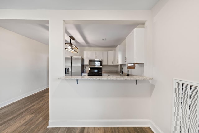 kitchen with white cabinetry, stainless steel appliances, dark hardwood / wood-style floors, light stone counters, and kitchen peninsula