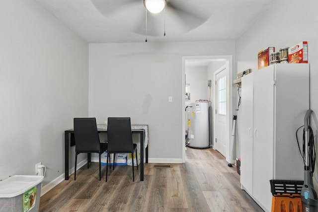 office space featuring water heater, ceiling fan, wood finished floors, and baseboards