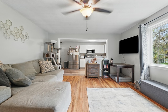 living area with light wood-style flooring and ceiling fan