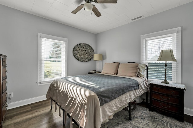 bedroom featuring ceiling fan, dark wood-type flooring, and multiple windows