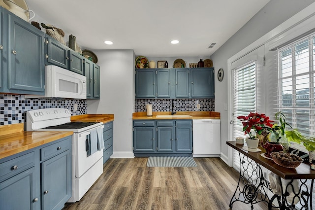 kitchen featuring white appliances, butcher block countertops, blue cabinets, and sink