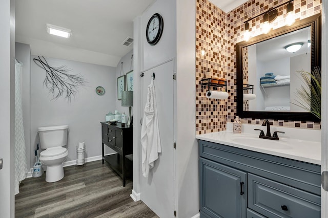 bathroom with decorative backsplash, hardwood / wood-style floors, vanity, and toilet