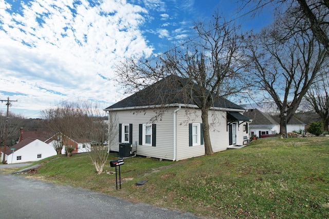 view of side of home featuring a lawn and central AC