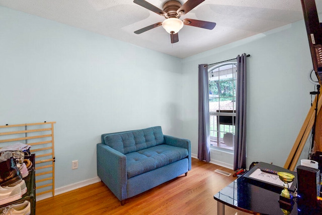 sitting room with ceiling fan, wood-type flooring, and a textured ceiling