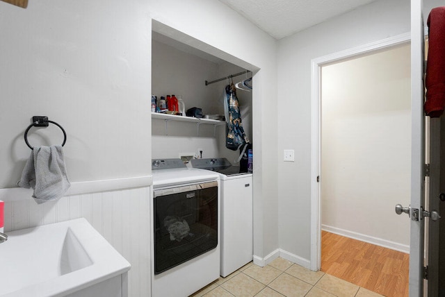 washroom with a textured ceiling, separate washer and dryer, light hardwood / wood-style flooring, and sink