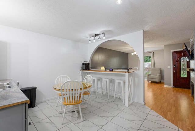 dining area featuring sink, a textured ceiling, and light hardwood / wood-style flooring