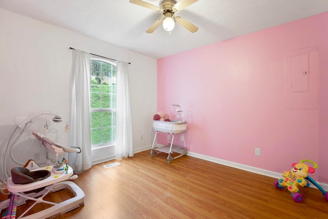 misc room with ceiling fan, light hardwood / wood-style floors, and electric panel