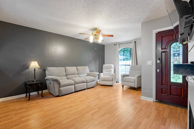 living room with ceiling fan, a textured ceiling, and light hardwood / wood-style flooring