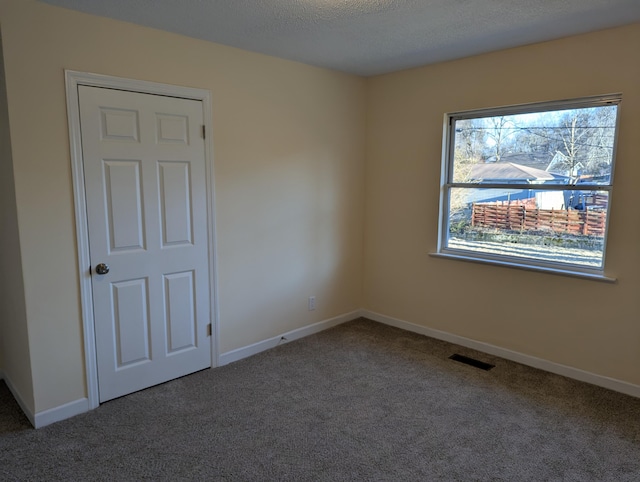 carpeted spare room with a textured ceiling