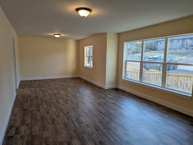 spare room featuring dark hardwood / wood-style flooring and a healthy amount of sunlight